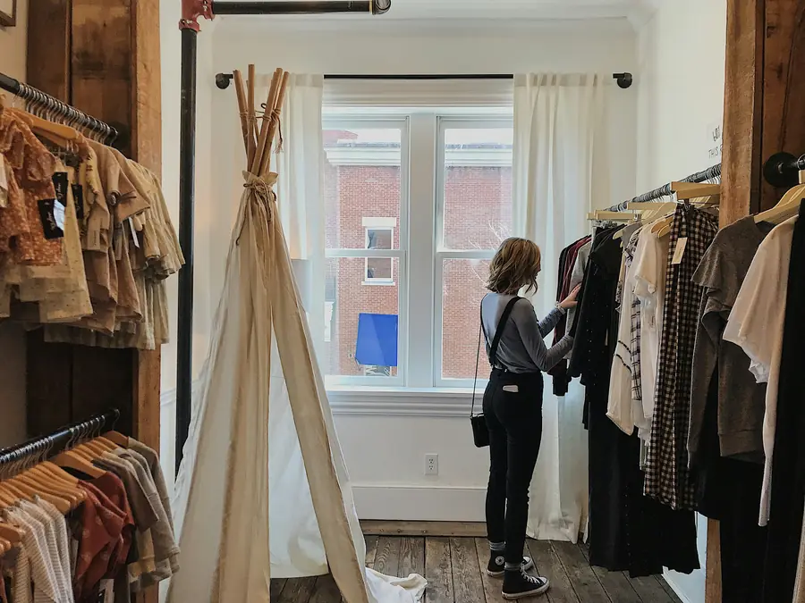 Cliente escolhendo roupas na arara da loja