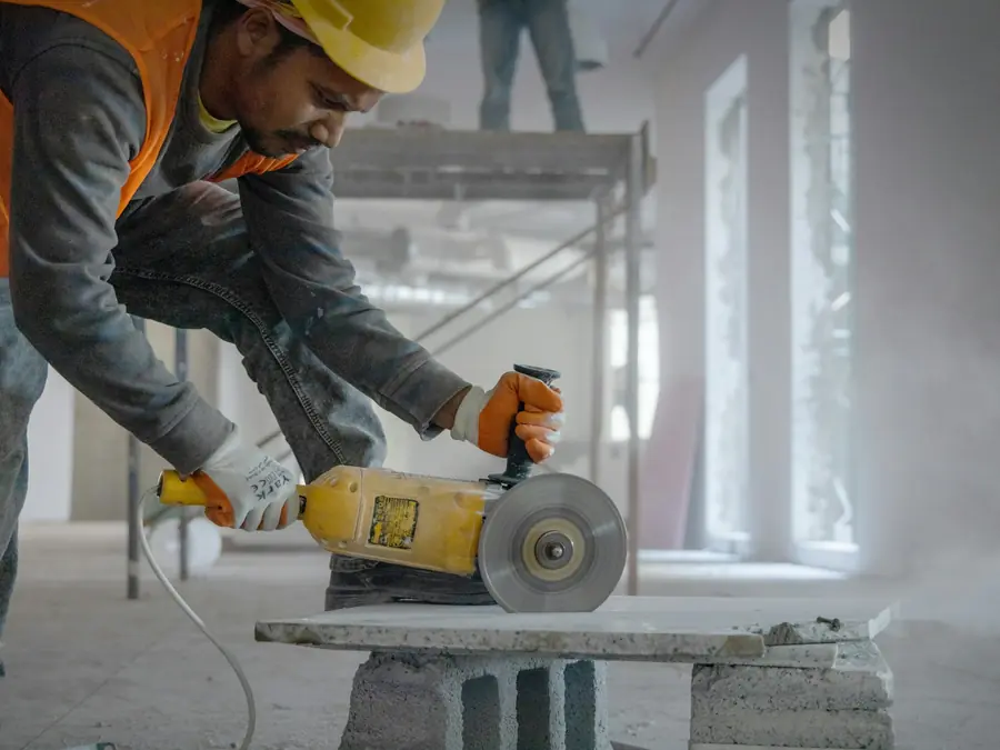 Pedreiro cortando material com esmerilhadeira na obra