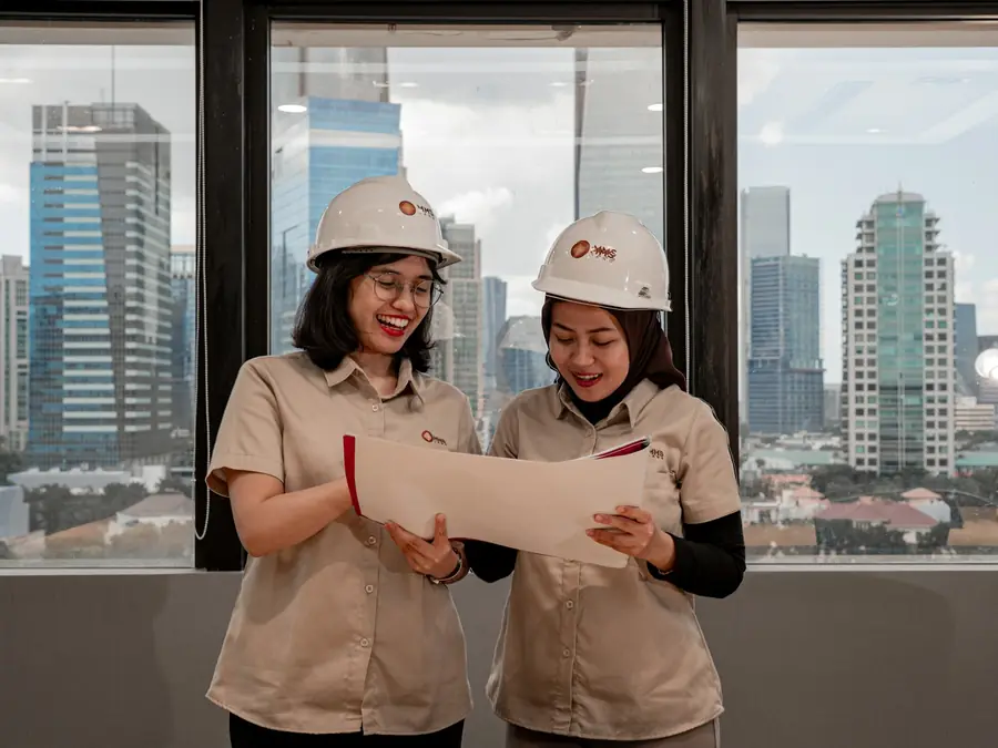 Duas engenheiras de capacete conferindo a planta de um projeto