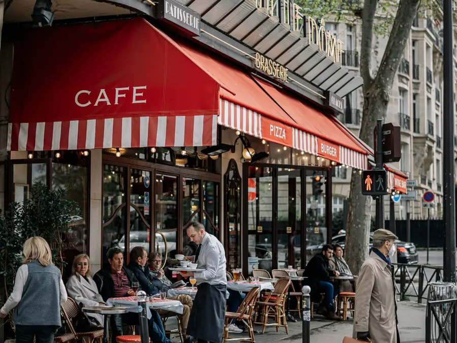 Café de esquina com toldo vermelho em Paris