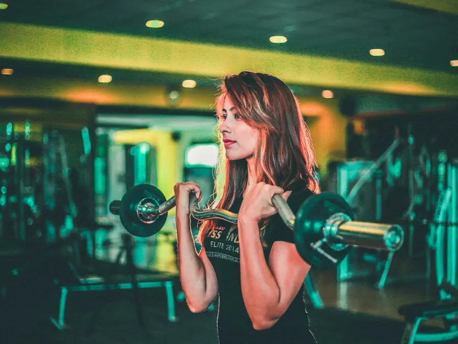 Mulher treinando bíceps em academia com luz neon