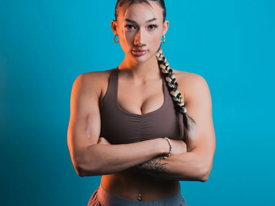Mulher de top esportivo com os braços cruzados em fundo azul