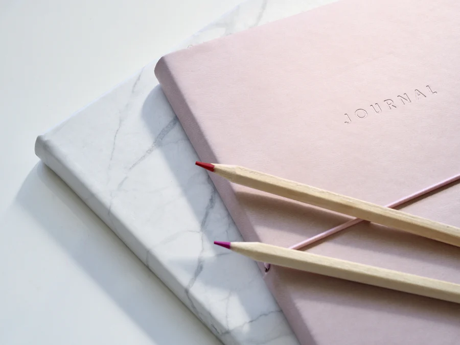 Caderno rosa e lápis de cor sobre a mesa