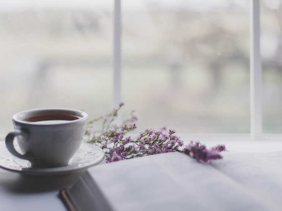 Xícara de chá ao lado de uma janela com flores de lavanda