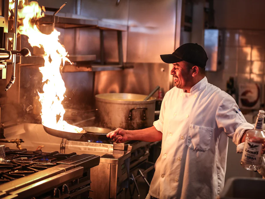 Cozinheiro flambando uma panela na cozinha da trattoria